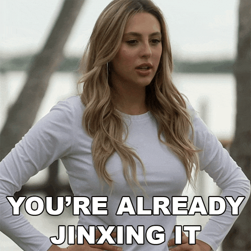 a woman in a white shirt has her hands on her hips and says " you 're already jinxing it "