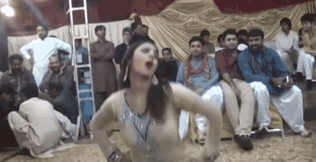a woman is dancing in front of a group of men