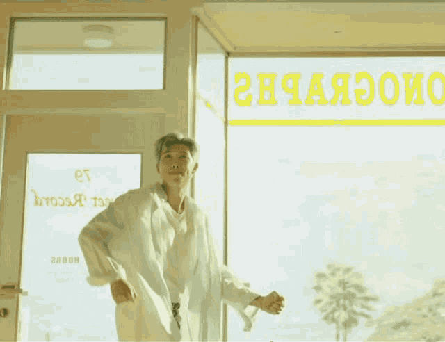 a man in a white coat is running in front of a sign that says 2h4aeooio