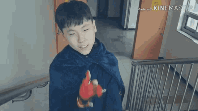 a boy wearing a blue cape is standing on a set of stairs made with kinemaster