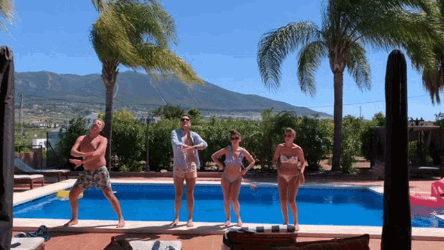 a group of people are posing for a picture in front of a swimming pool