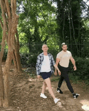 two men walking in the woods with one wearing a t-shirt that says adidas