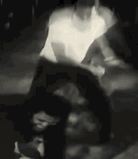 a black and white photo of a man in a white shirt standing next to a woman .