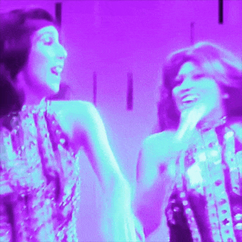 a couple of women are dancing in a purple light
