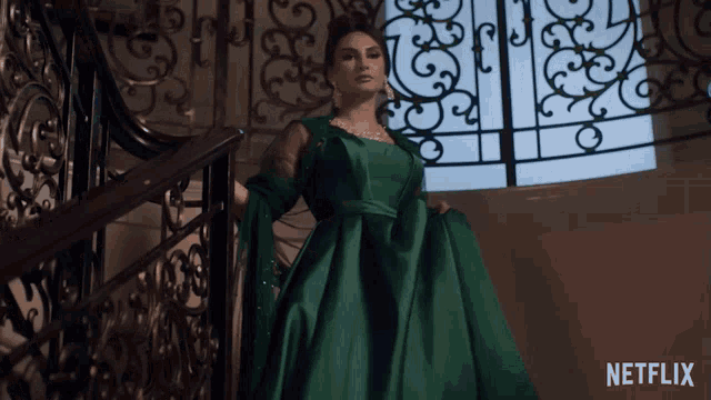 a woman in a green dress stands on a set of stairs with a netflix logo in the corner
