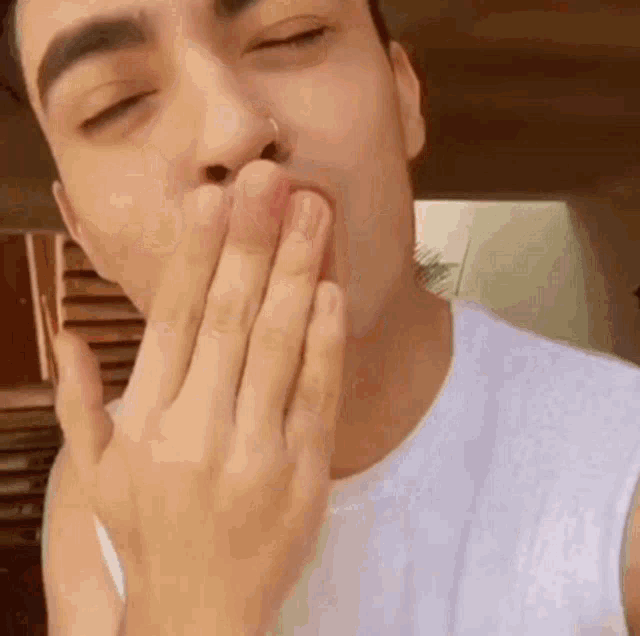 a man is blowing a kiss with his hand .