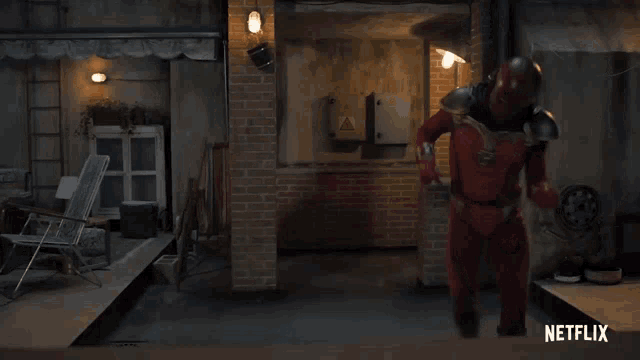 a man in a red superhero costume is standing in a room with netflix written on the bottom of the screen