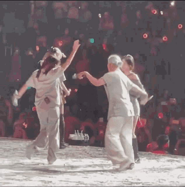 a group of people are dancing on a stage in front of a crowd of people .