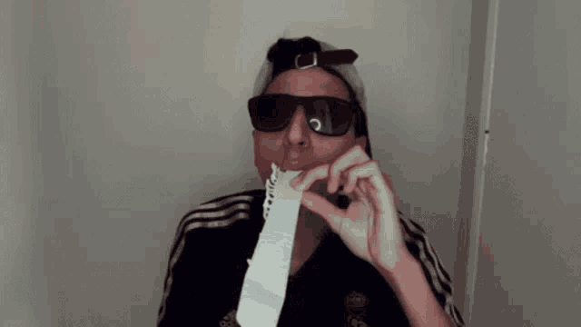 a man wearing a hat and sunglasses is making a funny face .