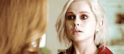 a woman with blonde hair is talking to another woman while wearing a red jacket .