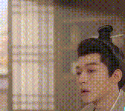 a man with a bun on his head is standing in front of a window in a room .
