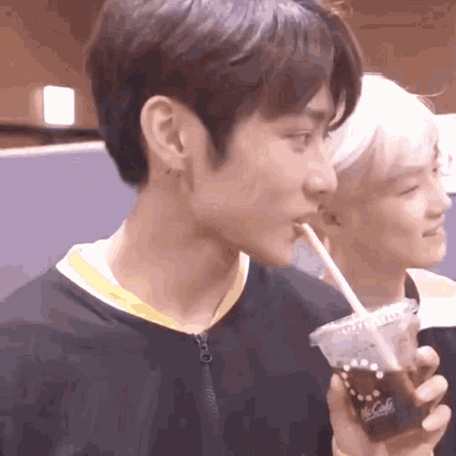 a young man is drinking a beverage through a straw .