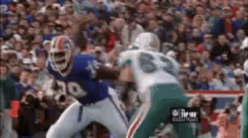 a football player wearing a blue jersey with the number 30 on it is being tackled by another player .