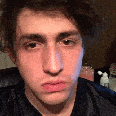 a close up of a young man 's face with a bottle of lotion in the background