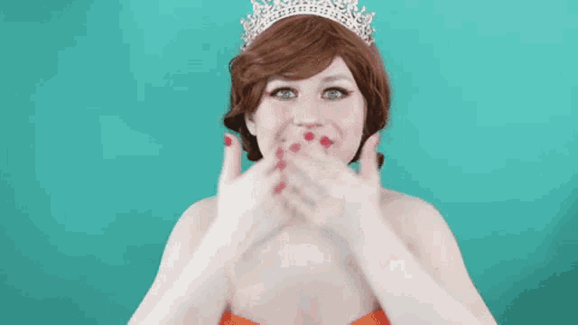 a woman wearing a tiara and a wig is blowing a kiss to the camera .