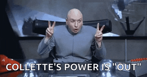 a bald man is sitting at a desk giving a peace sign and saying collette 's power is out .