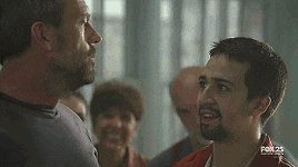 two men are standing next to each other and talking to each other .