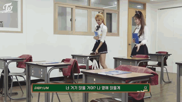 two girls standing in a classroom with a chalkboard that says dahyun on it