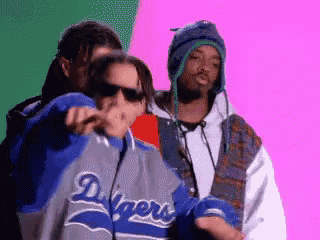 a man wearing a dodgers jacket is standing next to another man