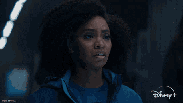 a woman in a blue jacket with disney + written on the bottom