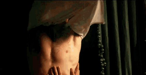 a man without a shirt is being touched by another man .