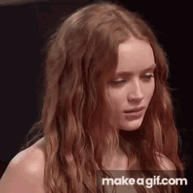a woman with long red hair is standing in front of a black background .