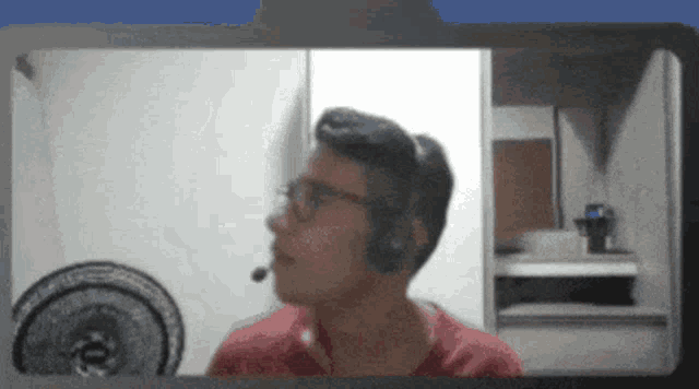 a man wearing headphones and glasses looks at a fan