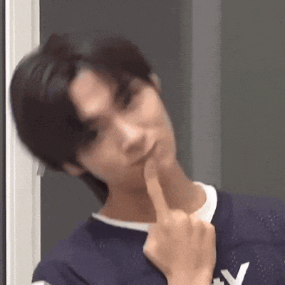 a young man is making a funny face and holding his finger to his chin .