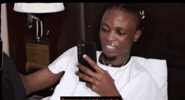 a man is sitting on a bed looking at his phone