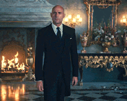 a man in a suit is standing in front of a fireplace