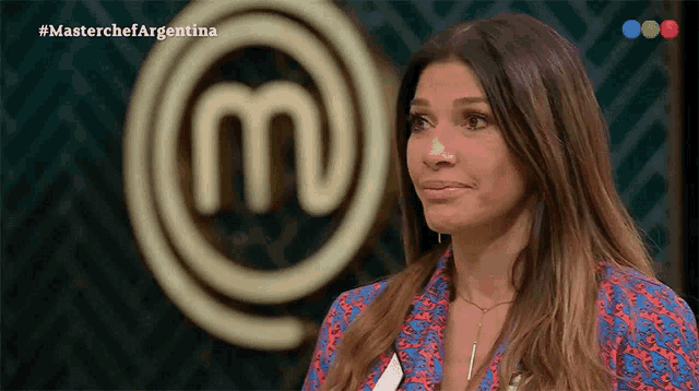 a woman is standing in front of a masterchef argentina logo