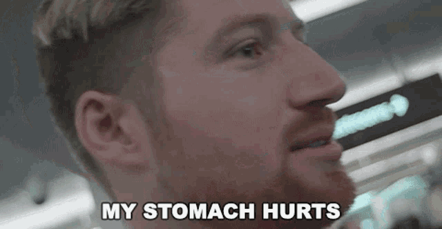 a man says " my stomach hurts " in front of a sign