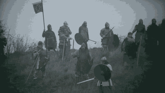 a group of medieval warriors standing on a hill with a flag that says x on it