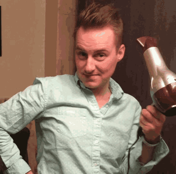 a man in a blue shirt is holding a hair dryer in his hand