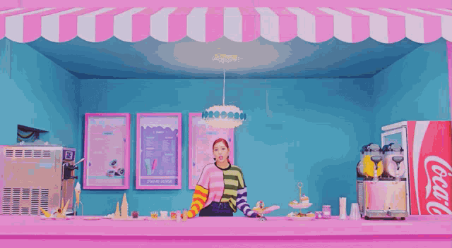 a woman stands behind a counter in front of a sign that says coca cola