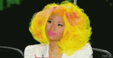 a woman with bright yellow hair and pink lips is sitting in a chair