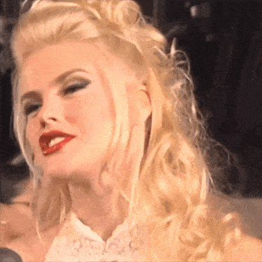 a woman with blonde hair and red lips is smiling