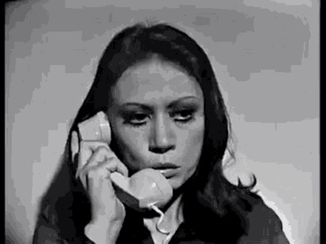 a black and white photo of a woman talking on a phone .