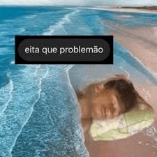 a person is sleeping on a beach with a blanket over their head .