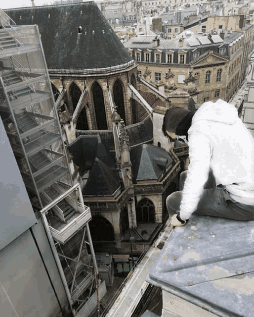 a man sits on the edge of a building looking down at the city