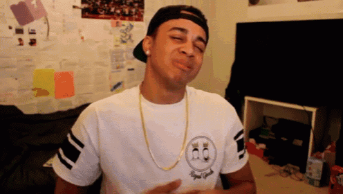 a man wearing a white shirt with a smiley face on the front is making a funny face