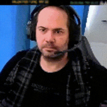 a bald man wearing headphones with a microphone looks at the camera