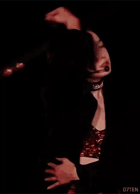 a woman wearing a black jacket and a red crop top stands on stage