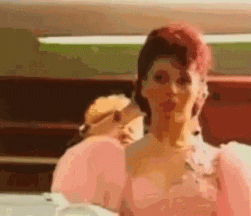 a woman with pink hair is wearing a pink dress and holding a pink balloon .