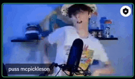 a young man is dancing in front of a microphone while wearing a hat .