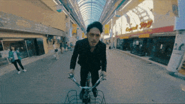 a man is riding a bike in front of a building that says ' crystal shop ' on it
