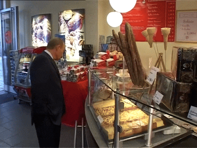 a man in a suit stands in front of a display case with ice cream cones on it