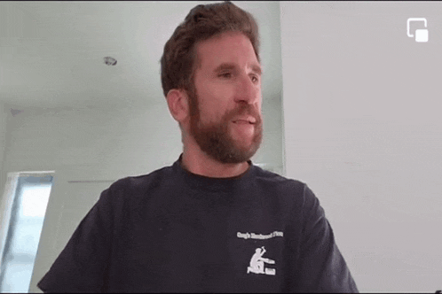 a man with a beard is wearing a black shirt .