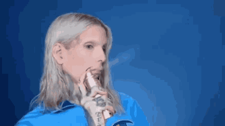 a woman with long blonde hair is holding a spray bottle in front of her face ..