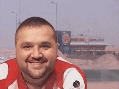 a man with a beard is smiling in front of a burger king